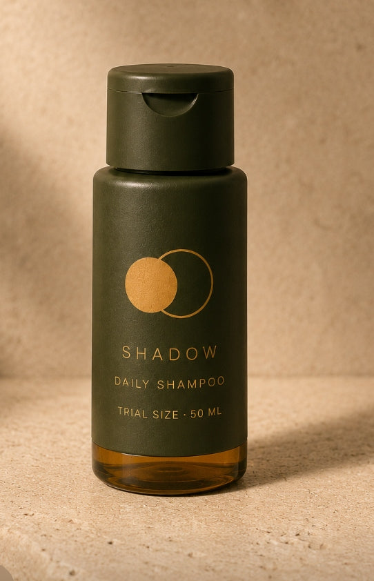 SHADOW Prøv-størrelse 50 ml — khakigrøn flaske med gennemsigtig ravfarvet bund og gyldent logo